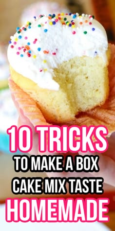 a hand holding a cupcake with white frosting and sprinkles on it