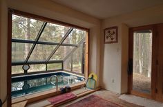 an indoor swimming pool in the middle of a room with windows looking out onto trees