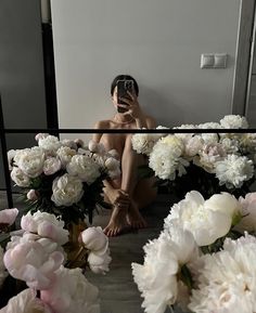 a woman is taking a selfie in front of some white and pink peonies