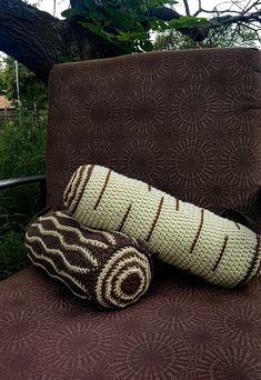 two knitted pillows sitting on top of a brown chair