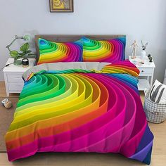 a bed covered in a rainbow colored comforter