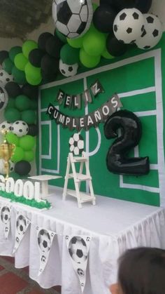 a soccer themed birthday party with green and black balloons, white tablecloths and decorations