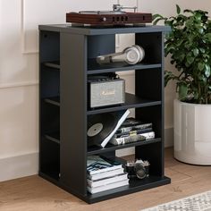 a record player is sitting on top of a book shelf next to a potted plant