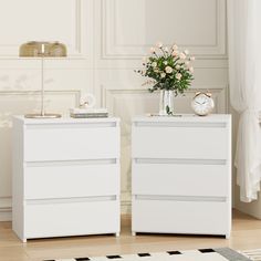 two white dressers with flowers in vase and clock on each side, sitting next to each other