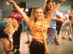 a group of young women dancing together in a dance studio with one woman holding her arms up