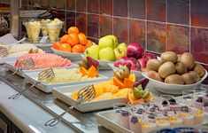 many different types of fruit are on display in bowls and trays at a buffet