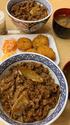 two bowls filled with food sitting on top of a wooden table next to other dishes