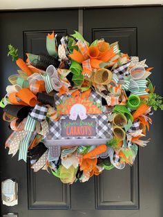 an orange and black wreath with carrots on the front door for halloween or fall