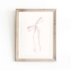 a white frame with a pink ribbon hanging on the wall