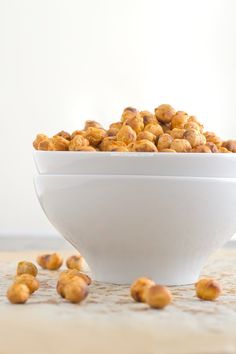 a white bowl filled with nuts on top of a wooden table