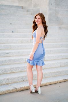 A model in a simple fitted dress features spaghetti straps and a lace-up back with ruffle hemline.