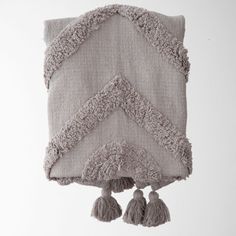 a gray pillow with tassels hanging from it