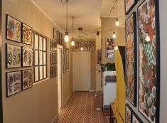 the hallway is lined with pictures and framed art on the wall, along with hanging lights