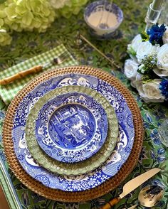 a blue and green table setting with plates, utensils and flowers on it