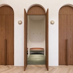 an empty room with wooden doors and a bench in the center, surrounded by white walls