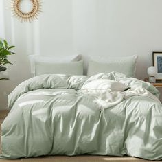 an unmade bed with light green sheets and pillows