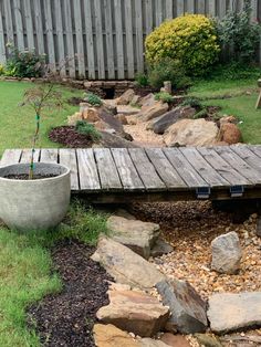 a garden with rocks and a wooden bridge