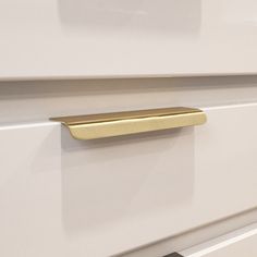 a close up of a drawer handle on a white cabinet