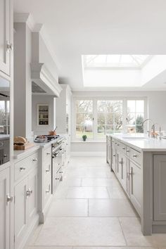 a large white kitchen with lots of counter space and appliances on the wall, along with skylights