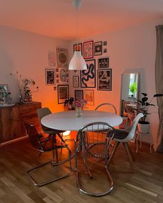 a white table and chairs in a room with pictures on the wall