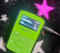 a green mp3 player sitting on top of a black and white rug with pink stars