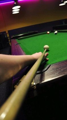 a person is playing pool in a dark room