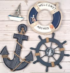 an anchor, steering wheel and life preserver are displayed on a white wooden background