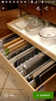 an open drawer in a kitchen filled with pots and pans on top of it