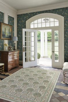 a living room with a large rug on the floor and french doors leading to an outside patio