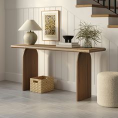 a wooden table sitting under a stair case next to a lamp and vase on the floor