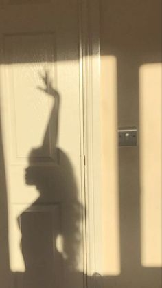 the shadow of a person standing in front of a door with their hand up and arm extended