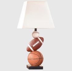 a lamp that is sitting on top of a basketball and football ball sculpture with a white shade