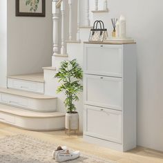 a white cabinet sitting in the middle of a living room next to a stair case