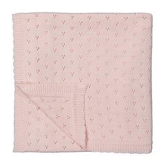 the pink knitted blanket is folded on top of a white background with red dots