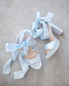 two pairs of white shoes with blue bows tied to them on the cement floor next to each other