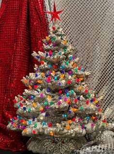 a small christmas tree sitting on top of a table next to a red cloth covered wall