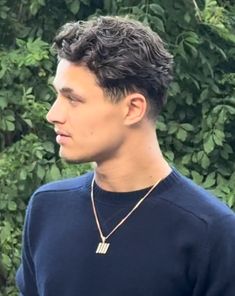 a young man wearing a blue shirt and necklace