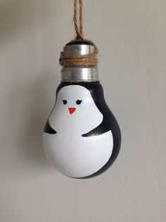 a penguin ornament hanging from a rope on a wall with a white background