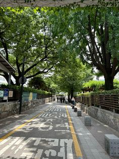 an empty street with people walking on the side walk and trees lining the walkways