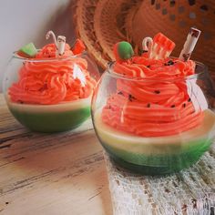 two bowls filled with orange and green desserts on top of a wooden table next to a straw hat