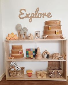 a wooden shelf filled with toys on top of a hard wood floor next to a white wall