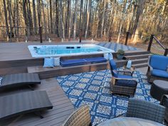 a hot tub sitting on top of a wooden deck next to a blue and white rug