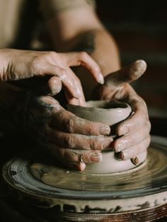 two hands on a potter's wheel making pottery