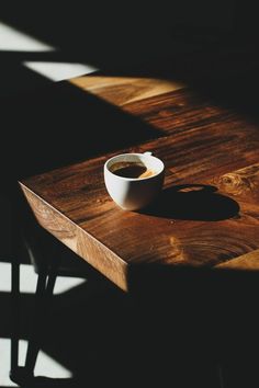 a cup of coffee sitting on top of a wooden table