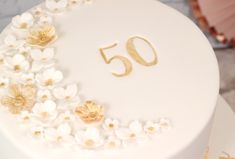 a white cake with gold numbers and flowers on it