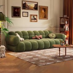 a living room with green couches and pictures on the wall above them, along with a coffee table