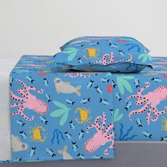 two blue boxes with pink and yellow sea animals on them, one is folded over the other