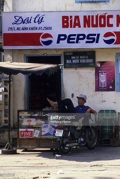 a man is sitting on a motorcycle in front of a store with an advertisement for pepsi