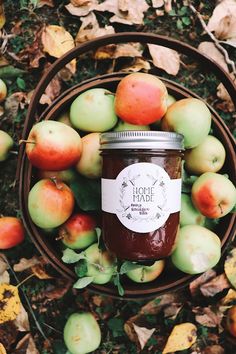 a jar of apple jam surrounded by leaves and apples