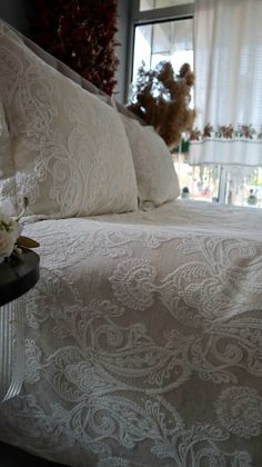 a bed with white linens and flowers on the headboard in front of a window